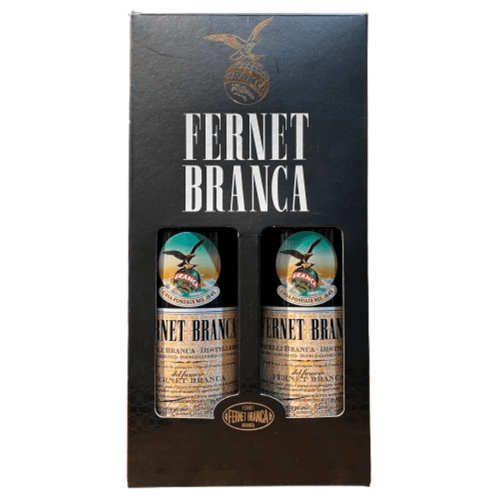 Botella de Fernet Branca Menta junto a cartel verde vertical con el texto 'BRANCAMENTA RICETTA ITALIANA 750 ml' sobre fondo blanco